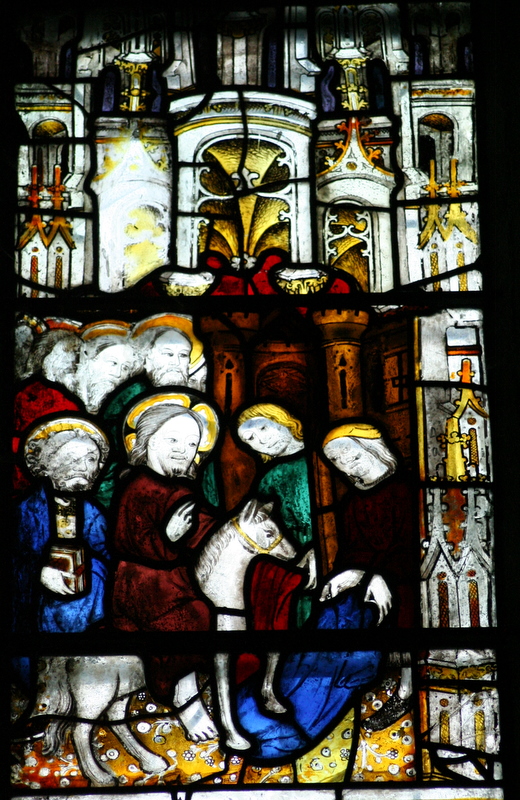 Stained glass panel depicting Jesus on a donkey surrounded by followers