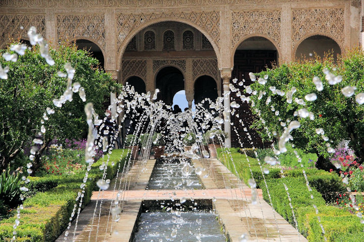 Photo of the Alhambra gardens at Granada, with central water feature and fountain, trees either side and the Alhambra Palace in the background