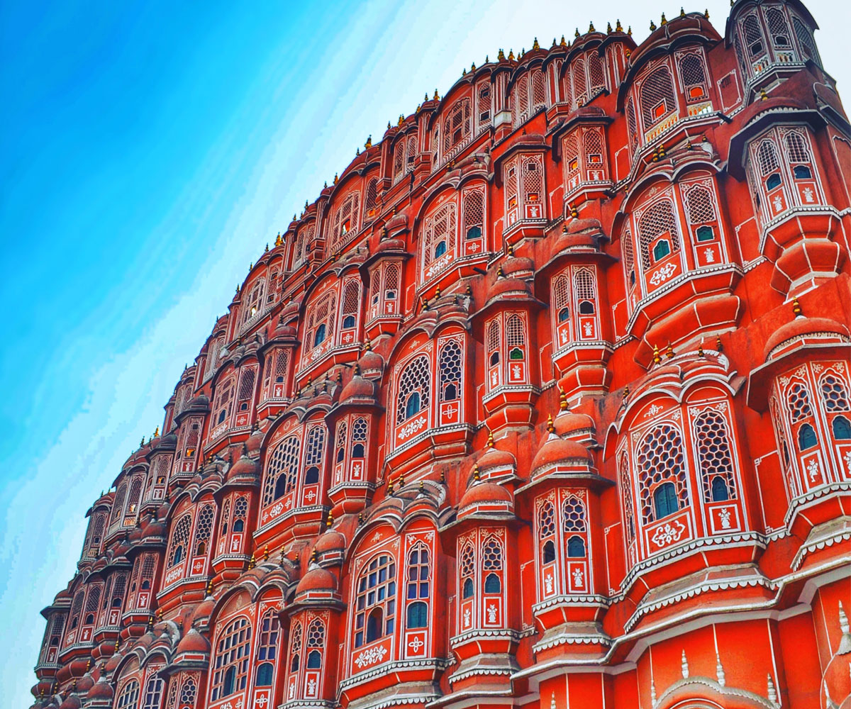 Hawa Mahal Palace, India. Tall red building decorated with white accents. 