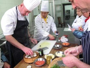 Andrew is given a lesson in how to cook dumplings in a steaming basket while Ian shows the Chinese chefs how to make pizza