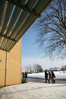 Students walk past building in snow