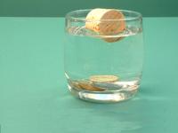 Coins sunk in water with cork floating on top.