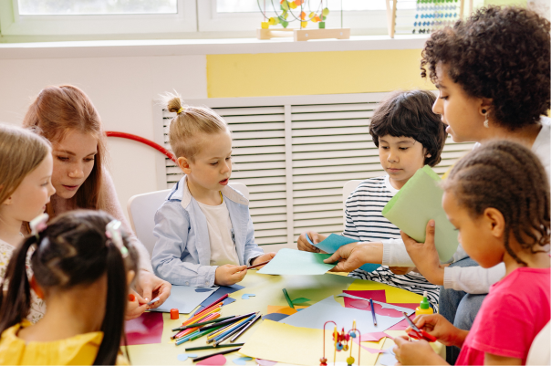 children at nursery sitting around a table with their teacher