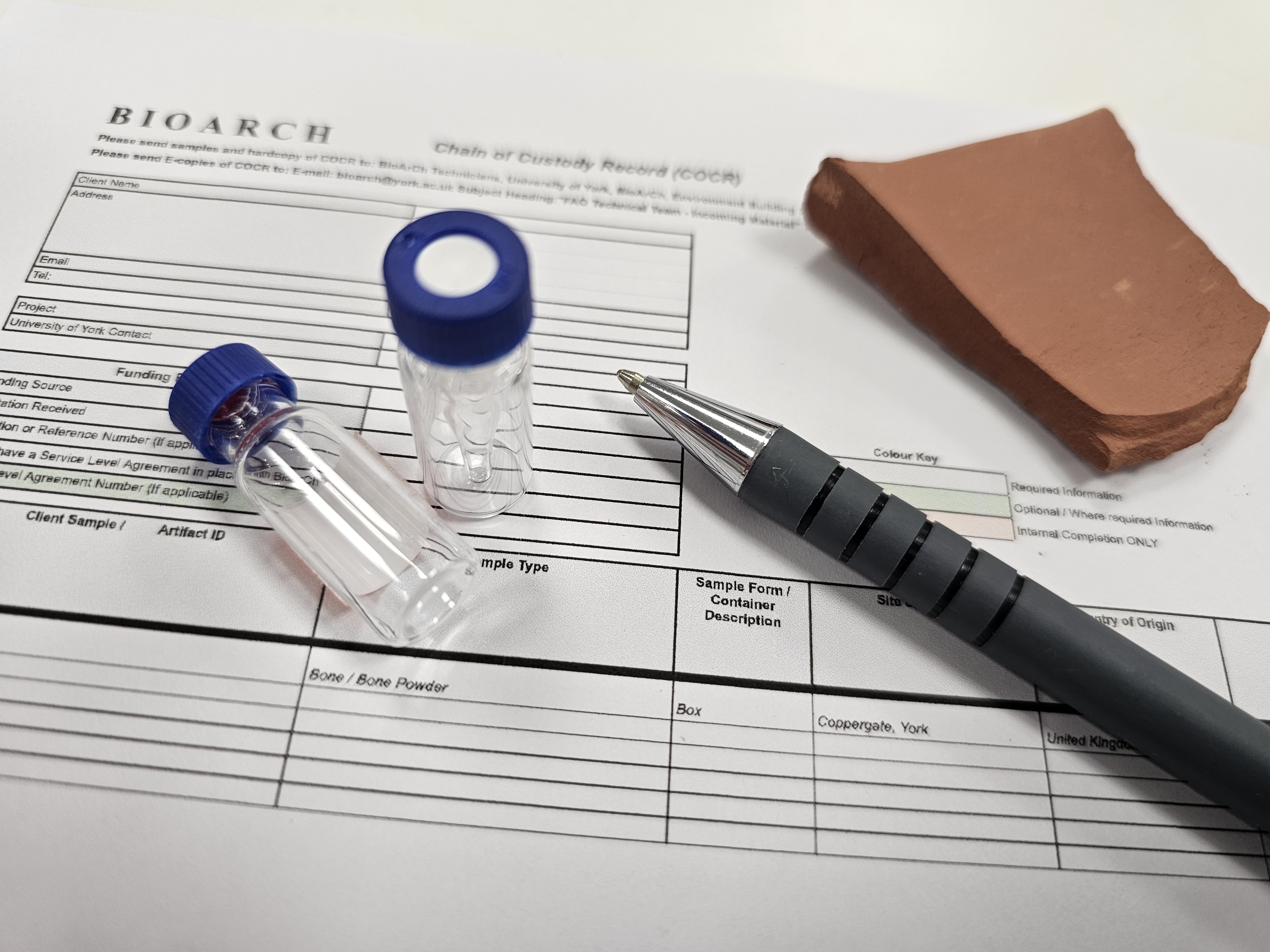 Printout of spectra with a pen, glass vials, pestle and mortar and piece of pottery