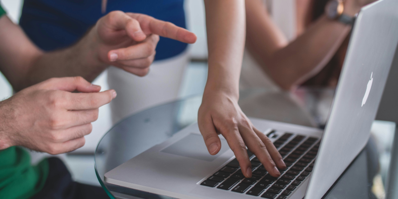 A group of course attendees huddled around a laptop