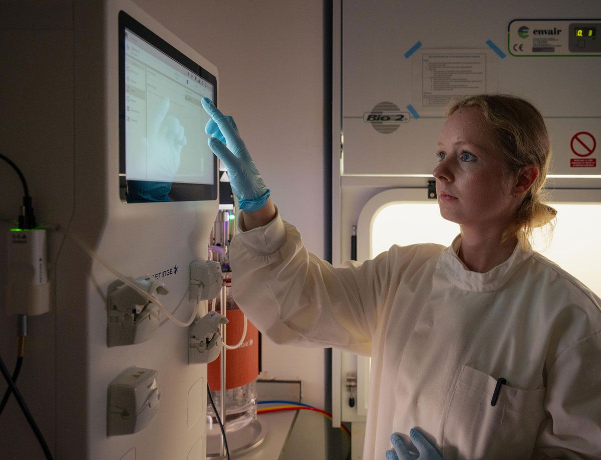A female scientist in a white coat studies a computer screen