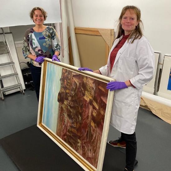 Two members of Art Collection staff holding a framed painting
