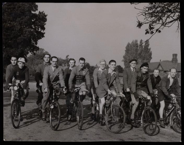 Six male blind members of the Wilberforce Memorial in a black and white photograph, pictured lined up on tandem cycles, with six male guides.