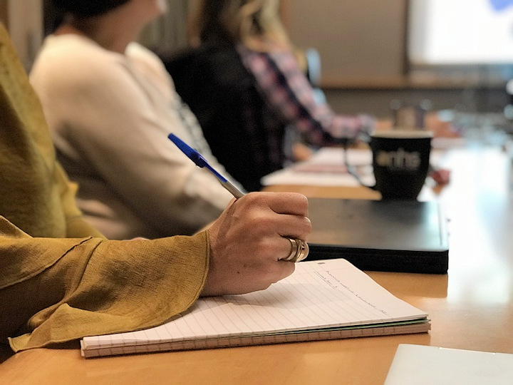 Students in a seminar take notes and view a presentation