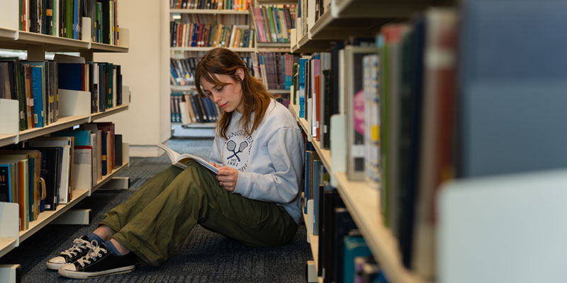 A student reading a book in the University library.