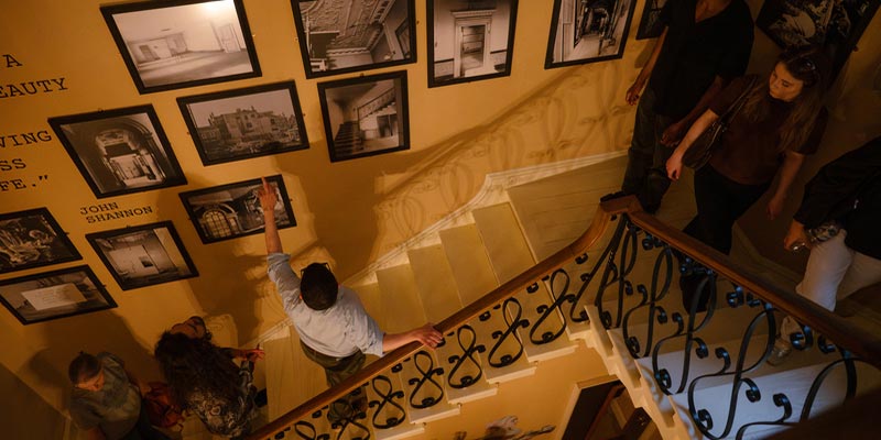 A group walking upstairs and looking at 18th-century artwork.