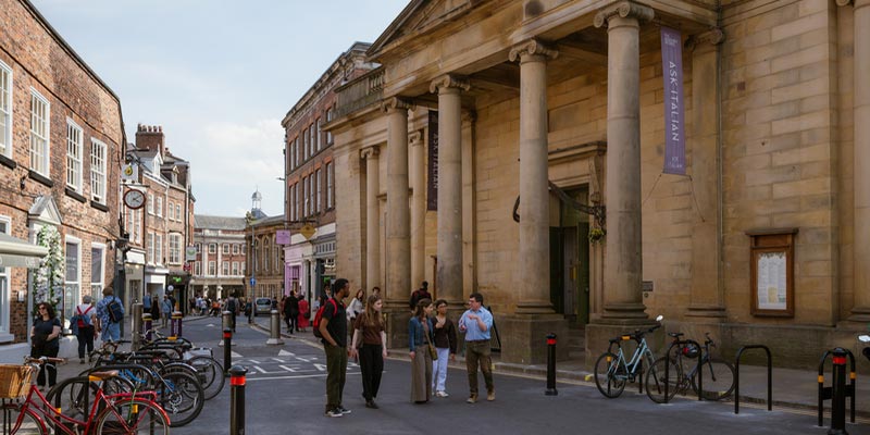 A group of student walking past the 18th century York Assembly Rooms building.