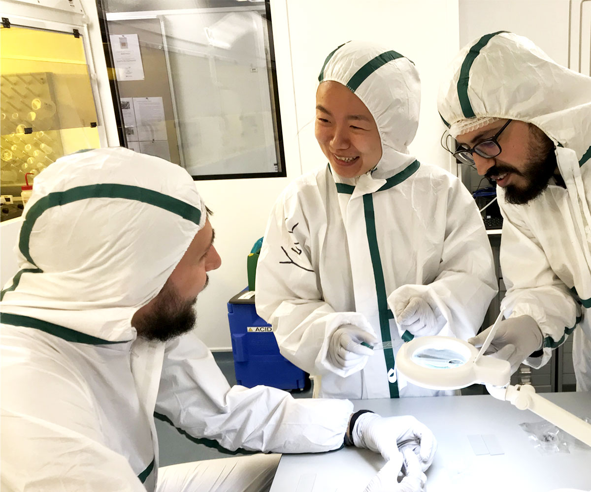 Two male and one female rsearcher in lab attire talking.