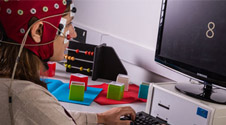 numerical cognition experiment taking place. Participant is wearing headgear while sitting at a computer.