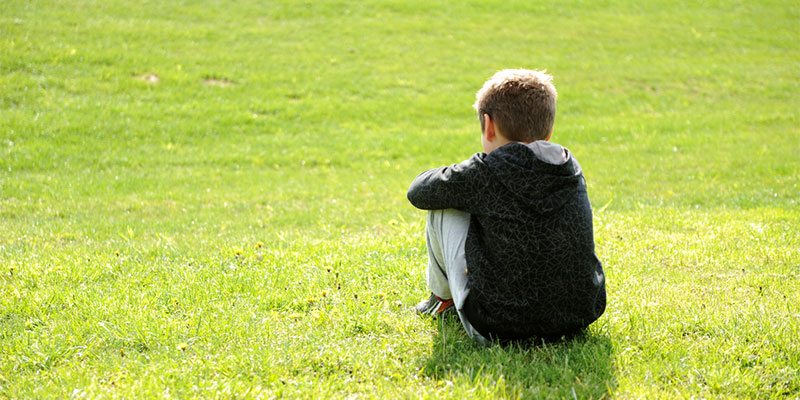 A child sitting alone on some grass