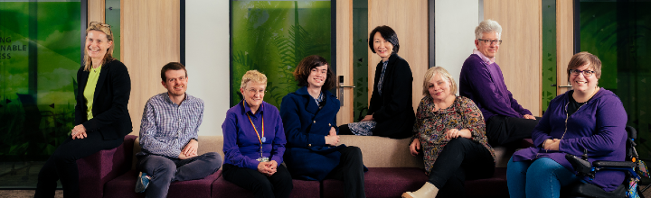 Various members of the eaccessibility group smiling and posing for the photo on a sofa.