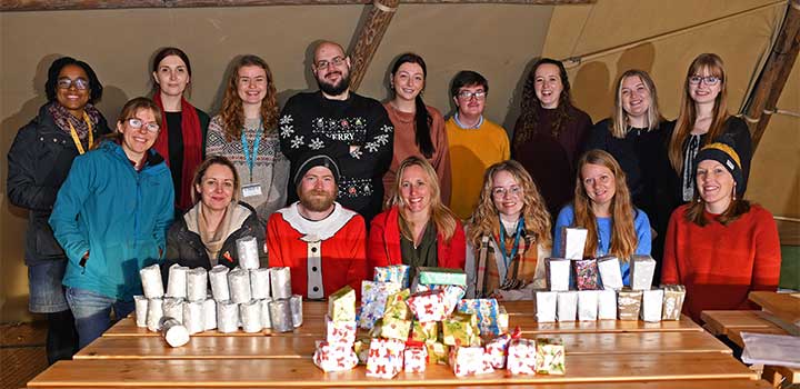 Members of staff sitting behind piles of presents they wrapped for care experienced and estranged students