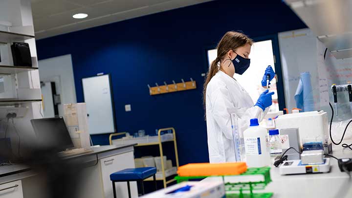 A student working in a covid-secure lab wearing gloves and a face covering