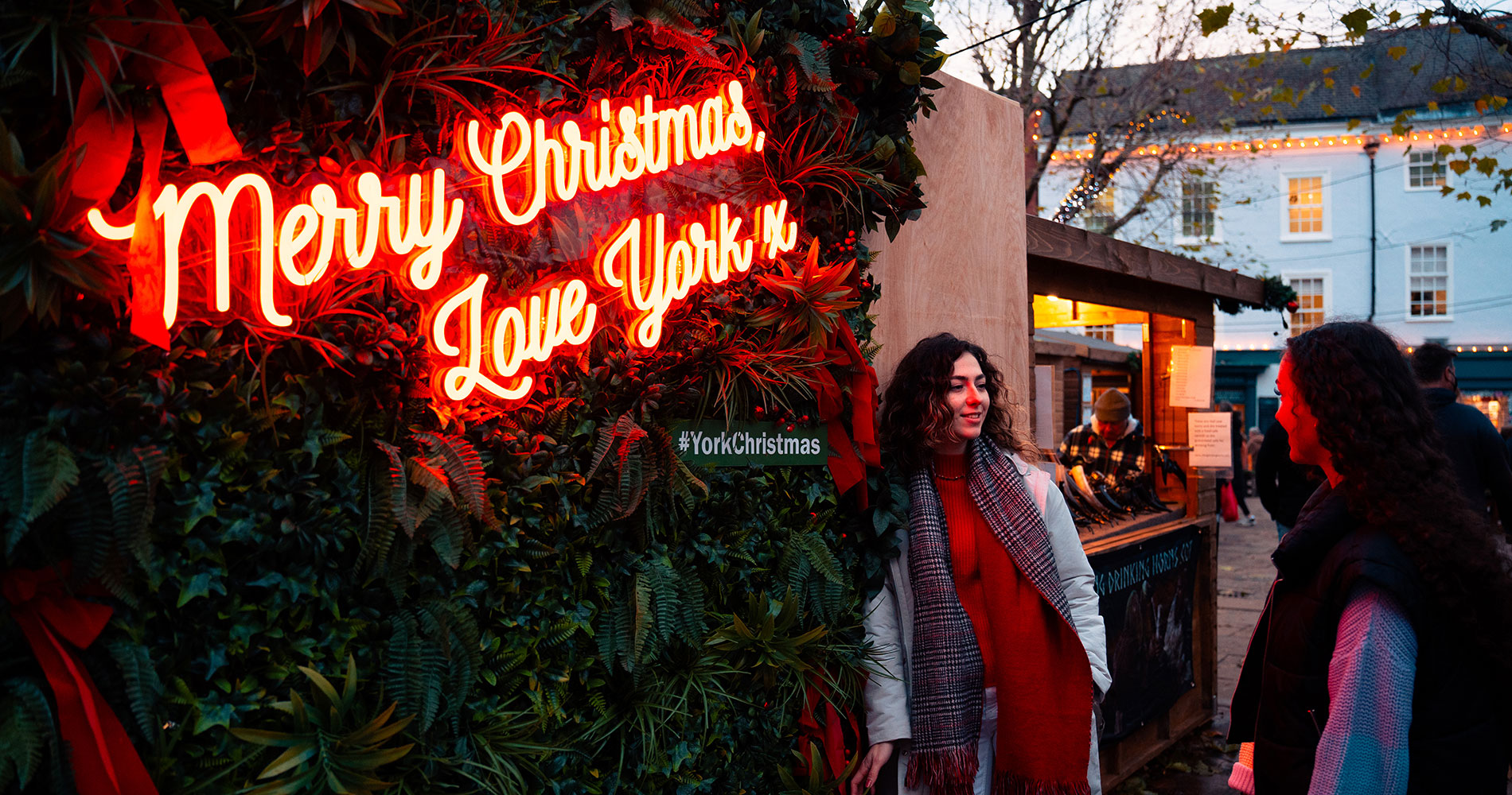 Students posing in front of a lit up sign saying 'Marry Christmas Love York'