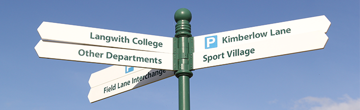A signpost against a blue sky. One sign points towards the Field Lane Interchange.