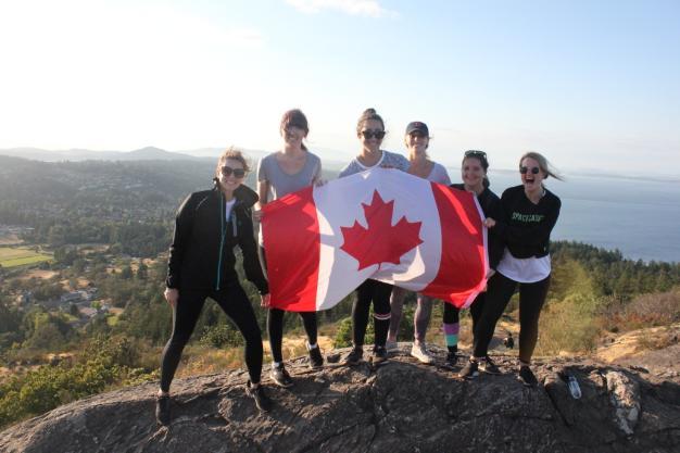 Group of students standing on Mt. Doug holding Canadian flag