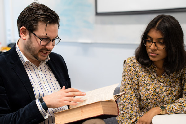 A lecturer and student reading a historical text