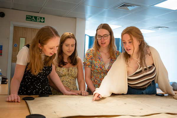 A group of students reading and discussing a historical text