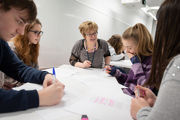 A teacher talking to a group of students around a table