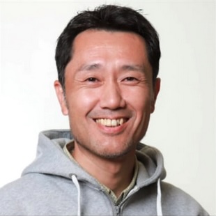 Headshot of Prof. Kazuhiro Manabe, wearing grey top with a hood