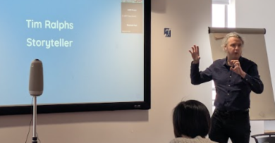 Storyteller Tim Ralphs, talking infront of a presentation screen